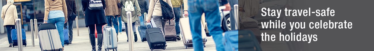 Stay travel-safe while you celebrate the holidays - Couple walking in airport with rolling luggage